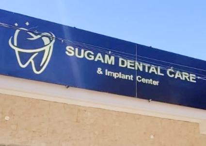Logo for Sugam Dental Care & Implant Center featuring a tooth symbol and clinic name.